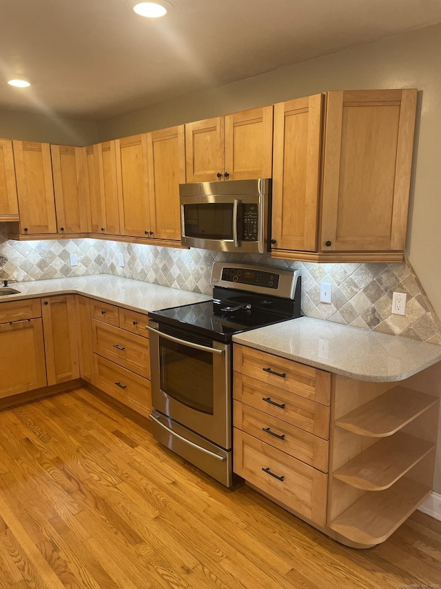 kitchen featuring stainless steel appliances, light hardwood / wood-style flooring, and tasteful backsplash