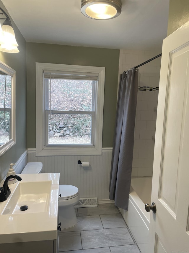 full bathroom with tile patterned floors, shower / bath combo with shower curtain, vanity, and toilet