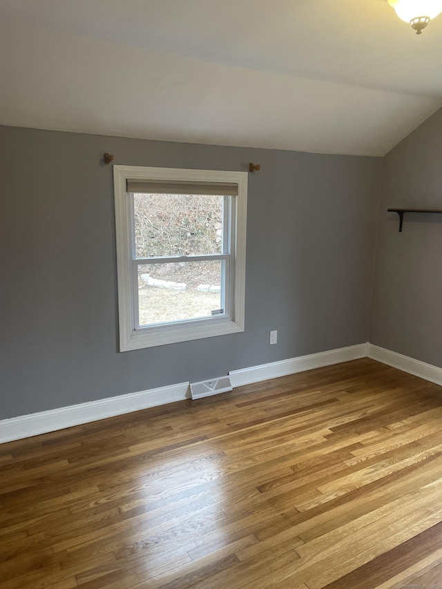 empty room featuring hardwood / wood-style floors and vaulted ceiling