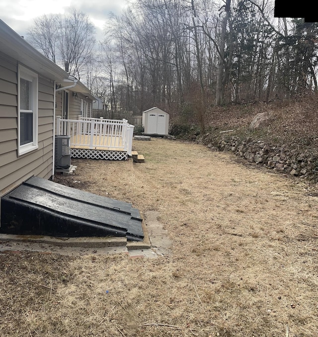 view of yard with cooling unit, a storage shed, and a deck