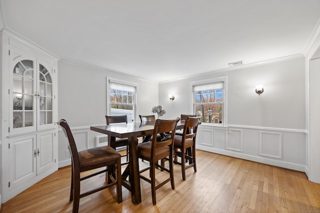 dining space with ornamental molding, a healthy amount of sunlight, and light wood-type flooring