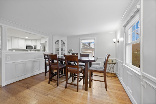 dining area with crown molding and light hardwood / wood-style flooring