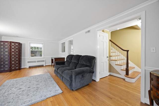 living room featuring hardwood / wood-style floors, radiator heating unit, and crown molding