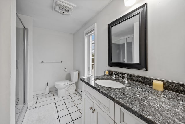 bathroom featuring tile patterned floors, vanity, toilet, and a shower with door