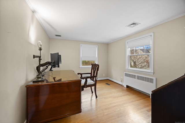 office space featuring plenty of natural light, light wood-type flooring, radiator heating unit, and ornamental molding