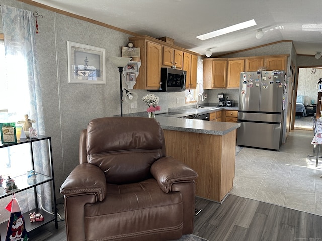 kitchen with kitchen peninsula, stainless steel appliances, light hardwood / wood-style floors, vaulted ceiling with skylight, and crown molding