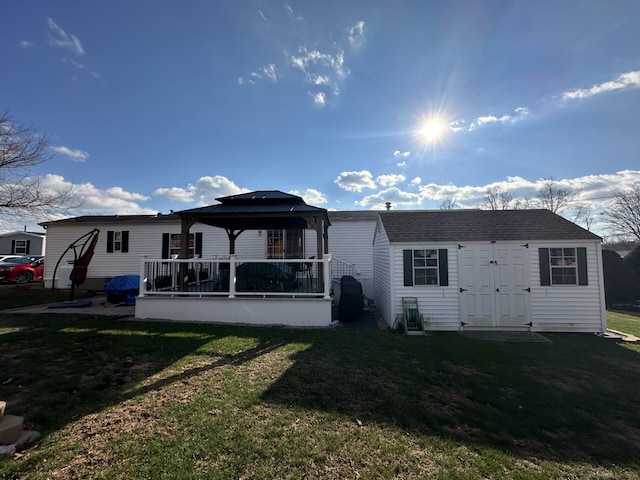 rear view of property with a lawn and a gazebo