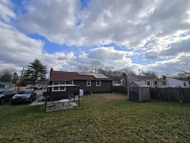 back of property with a lawn, solar panels, a storage unit, and a patio