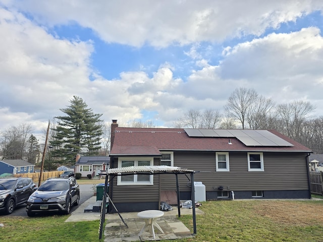 rear view of property with a lawn and solar panels