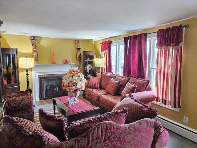 living room featuring a brick fireplace, hardwood / wood-style floors, and a baseboard heating unit