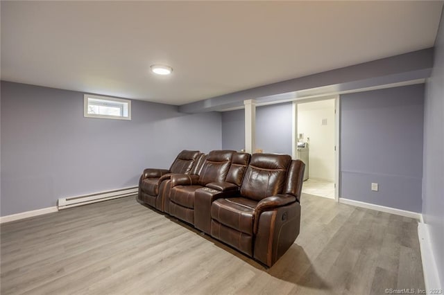 cinema room featuring a baseboard heating unit, wood finished floors, and baseboards