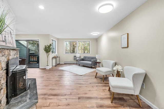 living room with hardwood / wood-style flooring, a wood stove, and a baseboard heating unit