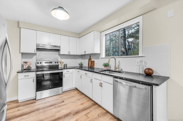 kitchen with appliances with stainless steel finishes, light wood-type flooring, white cabinetry, and sink