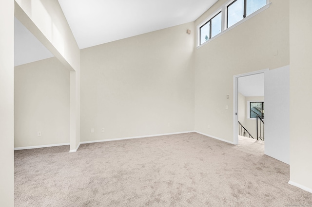 unfurnished living room featuring light carpet and a towering ceiling