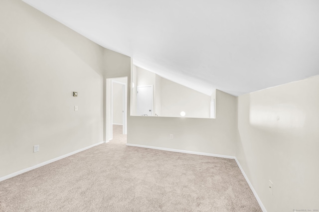 carpeted empty room featuring lofted ceiling