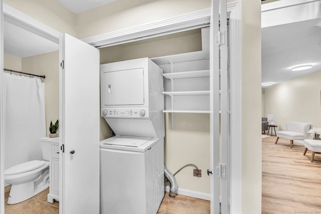 washroom with light hardwood / wood-style flooring and stacked washer and clothes dryer