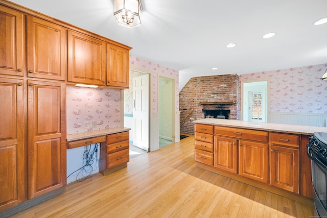 kitchen with black range with electric stovetop, light hardwood / wood-style floors, and a brick fireplace