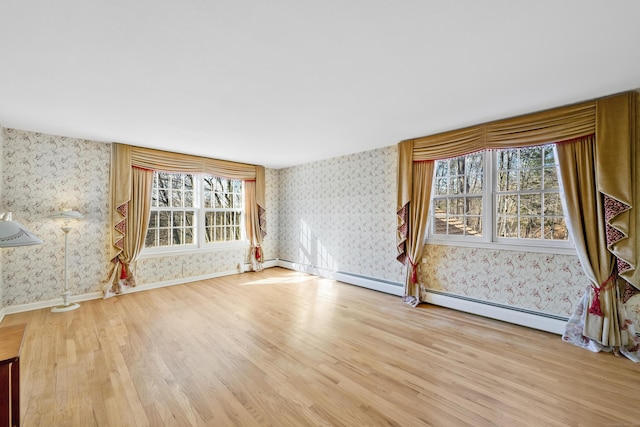 unfurnished living room featuring baseboard heating and wood-type flooring