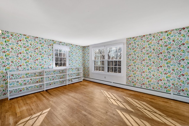 empty room featuring wood-type flooring and a baseboard radiator