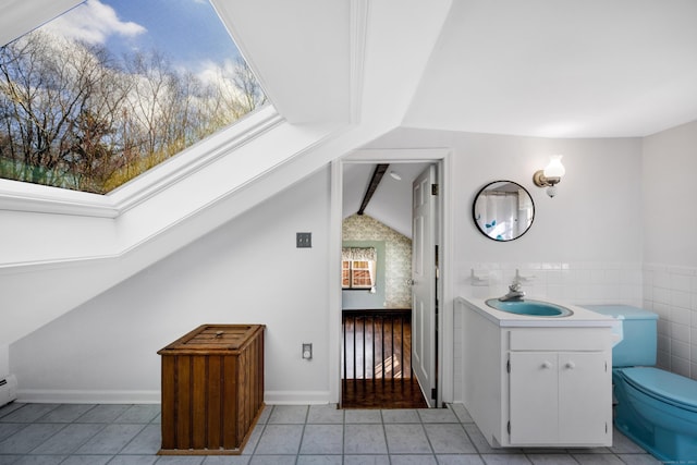 bathroom with tile patterned flooring, vanity, toilet, and vaulted ceiling