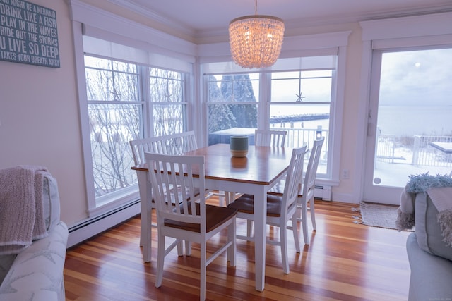 dining space featuring a chandelier, light hardwood / wood-style flooring, a baseboard heating unit, and crown molding