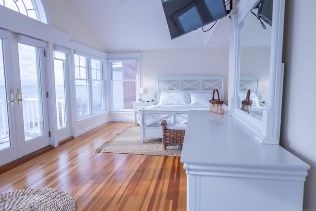 bedroom with french doors, light hardwood / wood-style floors, and lofted ceiling