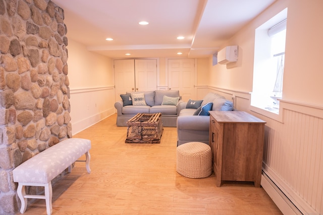 living room featuring a wall mounted AC, light hardwood / wood-style floors, and a baseboard heating unit