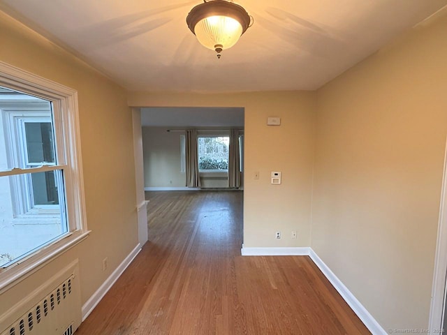 hallway featuring radiator heating unit and hardwood / wood-style floors