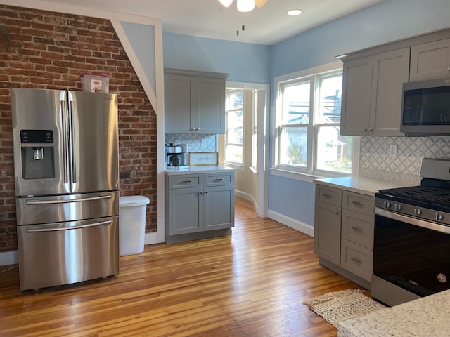 kitchen featuring appliances with stainless steel finishes, backsplash, gray cabinets, and light hardwood / wood-style flooring