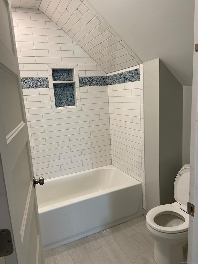 bathroom with toilet, tiled shower / bath, and lofted ceiling