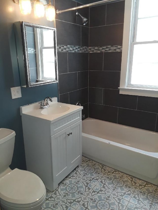 full bathroom with plenty of natural light, toilet, tiled shower / bath, and vanity