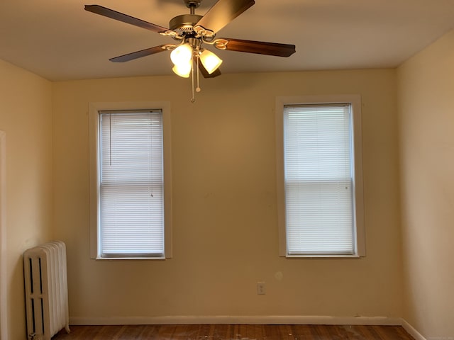 spare room with dark hardwood / wood-style flooring, radiator, a healthy amount of sunlight, and ceiling fan