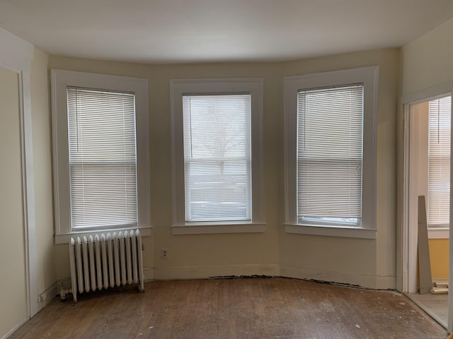 unfurnished room with radiator heating unit and hardwood / wood-style floors