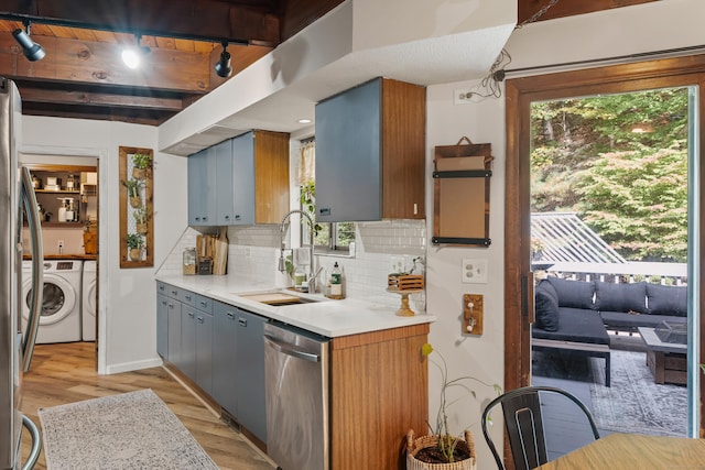 kitchen featuring light wood-type flooring, stainless steel dishwasher, sink, beam ceiling, and separate washer and dryer