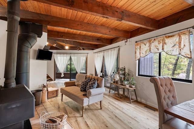 living room with a wood stove, a wealth of natural light, and wooden ceiling