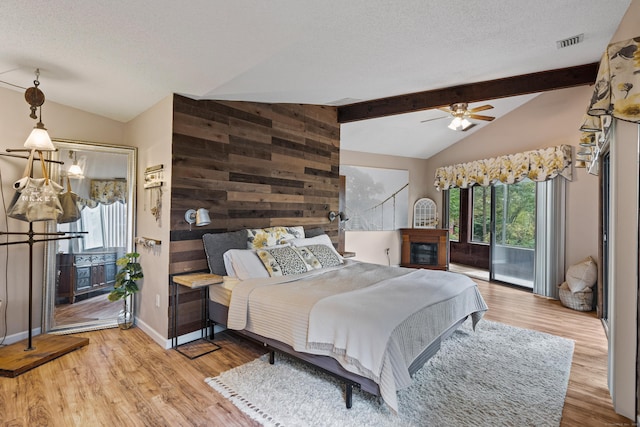 bedroom featuring vaulted ceiling with beams, wood walls, ceiling fan, and wood-type flooring