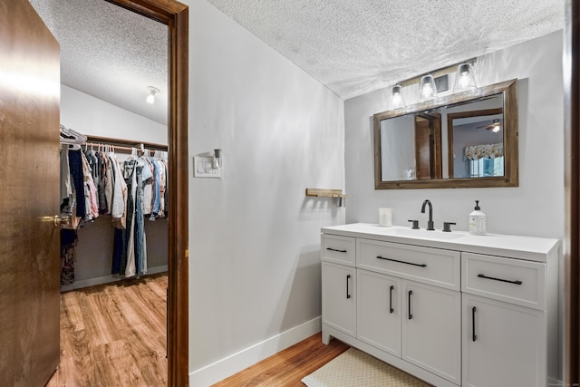 bathroom with vanity, hardwood / wood-style floors, a textured ceiling, and vaulted ceiling