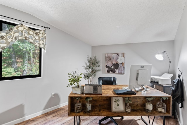 office featuring a textured ceiling, hardwood / wood-style flooring, vaulted ceiling, and plenty of natural light