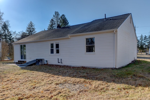 rear view of house with cooling unit and a lawn