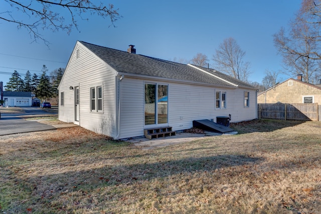 rear view of house featuring cooling unit and a lawn