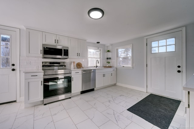 kitchen featuring tasteful backsplash, white cabinets, and stainless steel appliances