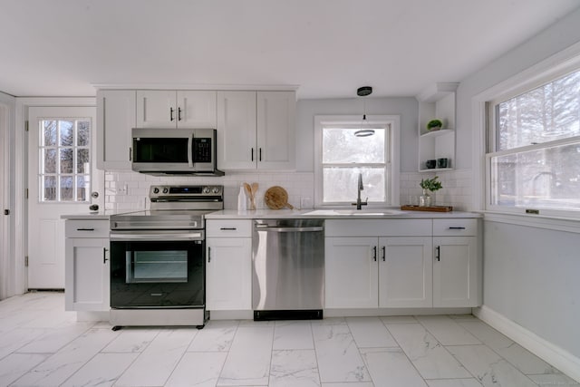 kitchen featuring tasteful backsplash, hanging light fixtures, white cabinets, and stainless steel appliances