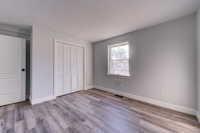 unfurnished bedroom with light wood-type flooring and a closet