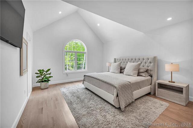 bedroom with lofted ceiling and light hardwood / wood-style floors