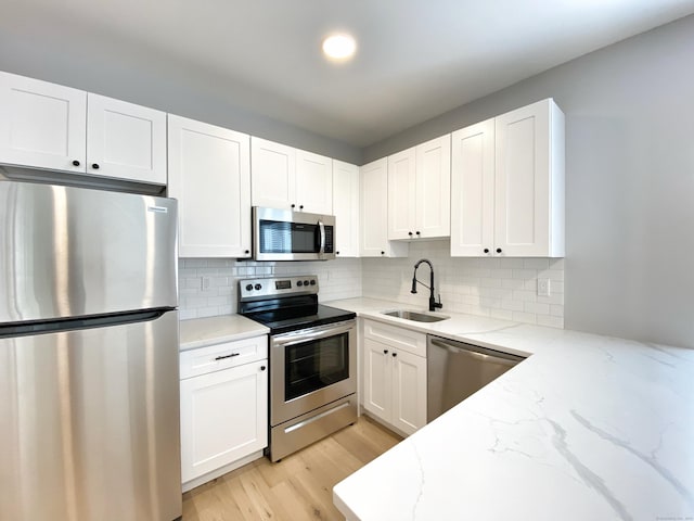 kitchen with light stone counters, sink, white cabinets, and appliances with stainless steel finishes