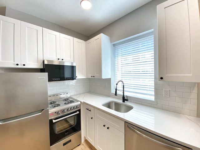 kitchen featuring sink, appliances with stainless steel finishes, backsplash, light stone counters, and white cabinets