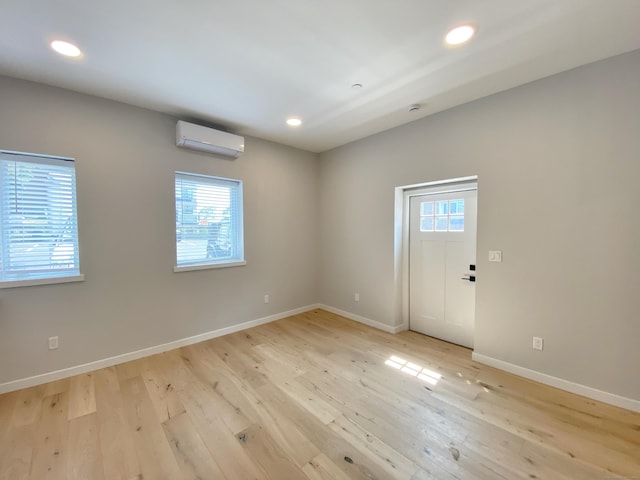 empty room with a wall mounted air conditioner and light hardwood / wood-style flooring