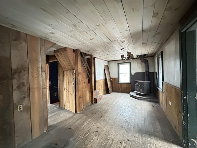 interior space featuring hardwood / wood-style flooring, a wood stove, wooden ceiling, and wood walls