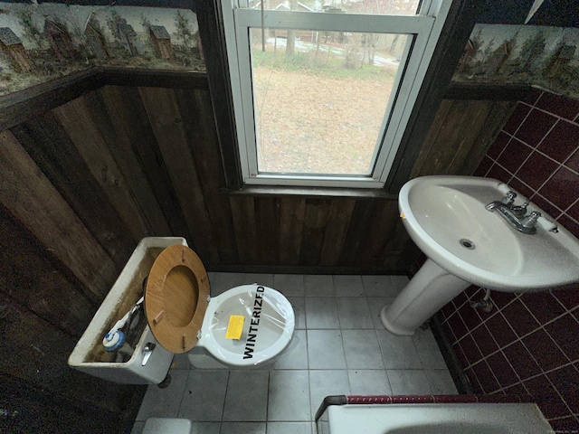 bathroom with tile patterned flooring, a bath, tile walls, and wood walls