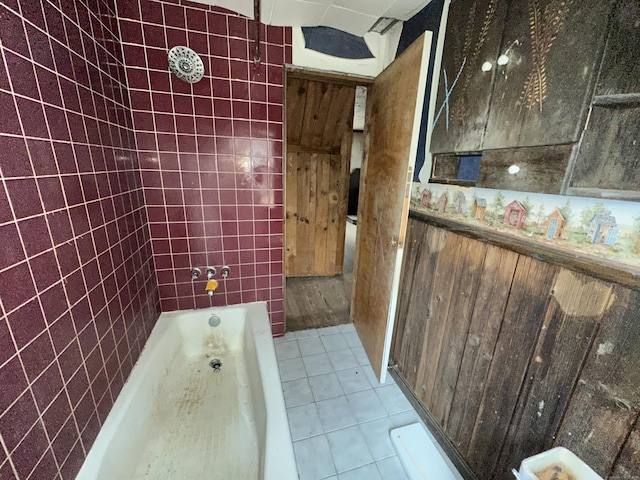 bathroom featuring tile patterned floors, a bathtub, and tile walls